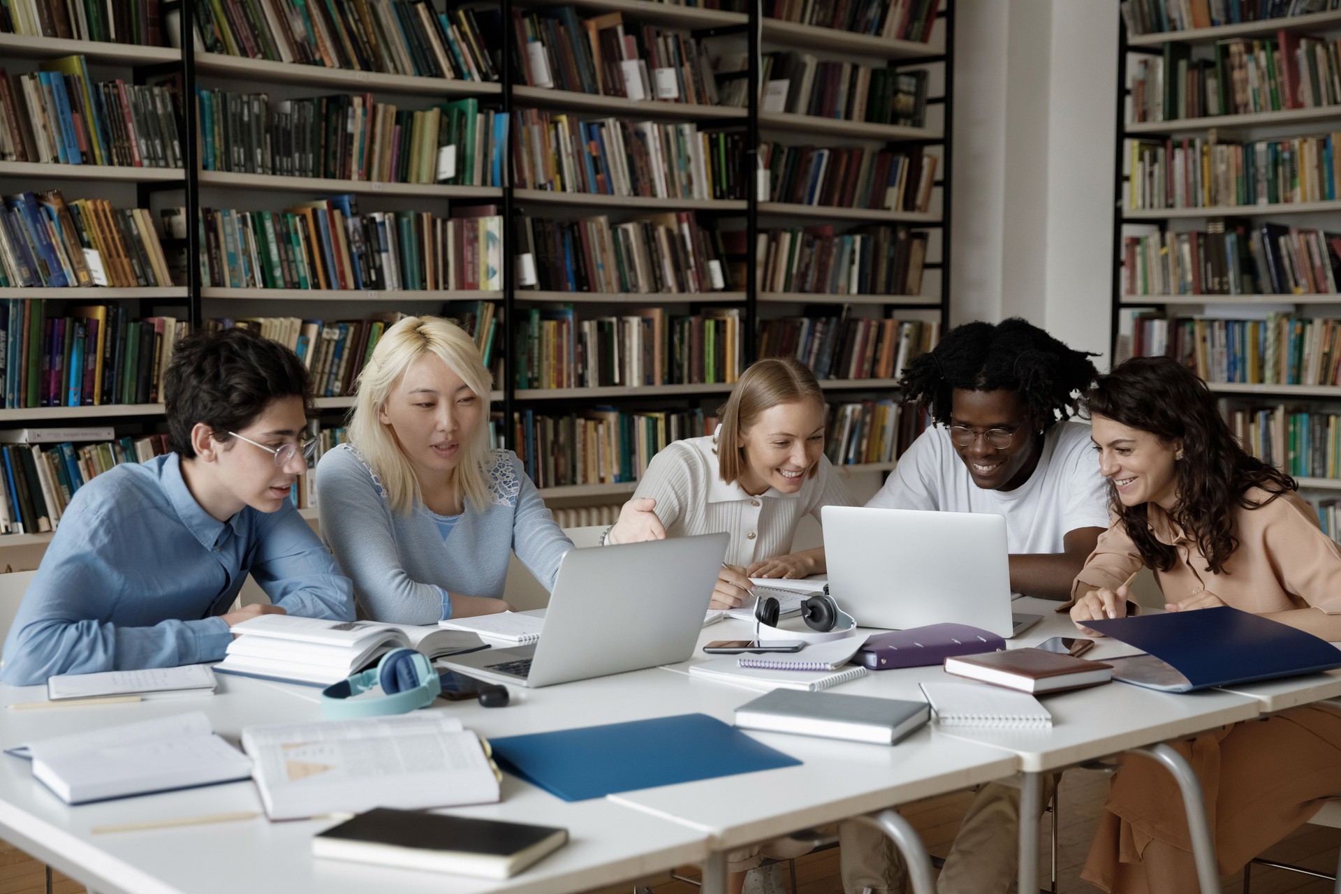 Group of multiethnic students studying together in library using laptop