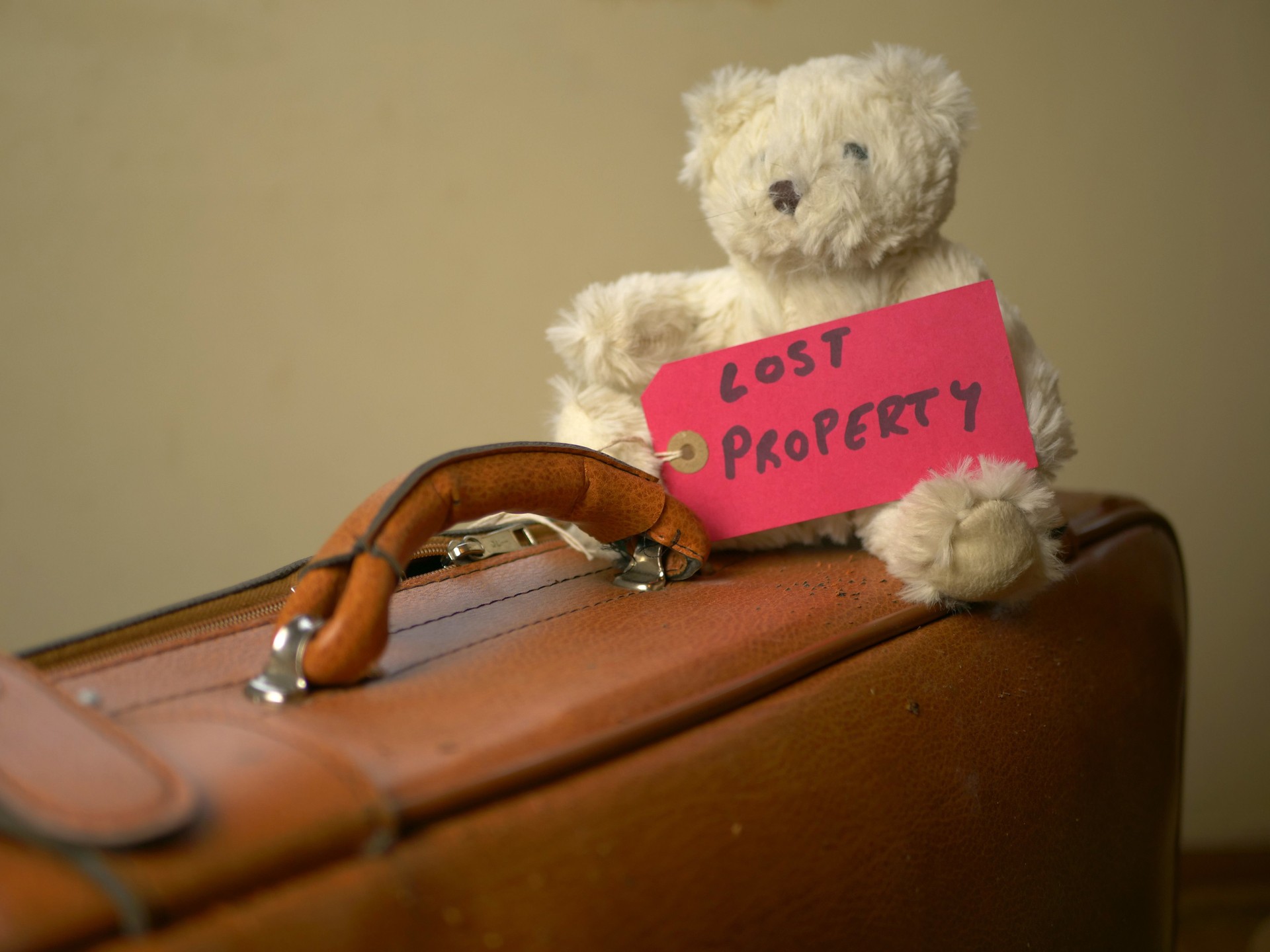 Bear toy on an old suitcase with a "Lost property" label tag